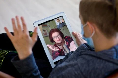 Rear view of a guy talking on a video call with a smiling elderly grandmother Stock Photos