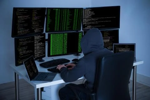 Rear view of hacker using computers to steal data in office Stock Photos