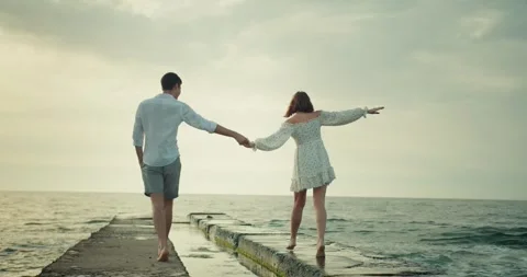 Rear view of a happy couple guy and girl in a white dress and shirt walking Stock Footage 283834824