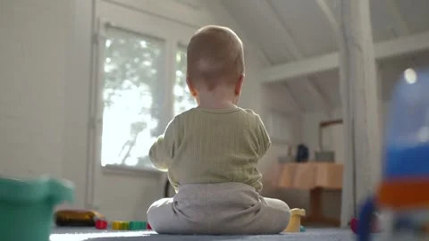 Rear view of infant sitting on playmat in bright room Stock Footage 341628560
