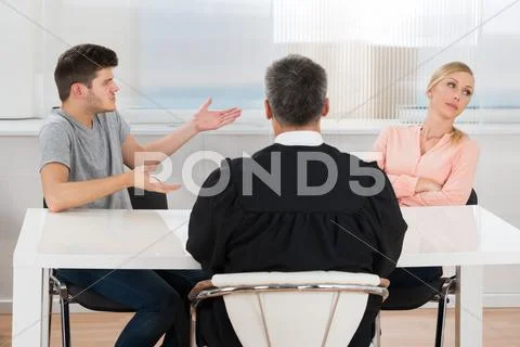Rear View Of Judge Sitting In Front Of A Young Couple Having Conflict In Cour Stock Photos