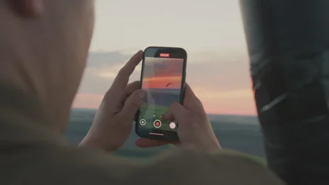 Rear View of Lady Filming Sunset and Paraglider from Hot Air Balloon Stock Footage 317171265