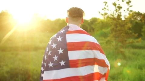 Rear view of a large American flag on the shoulders of a man. The memory of the Stock Footage 108659994