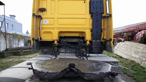 Rear view of large yellow semi-truck showing greasy fifth wheel coupling plate, 스톡 동영상 323913472