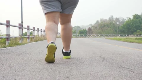 Rear view, low angle shot of unrecognizable fat woman running outdoors Stock Footage 182435580