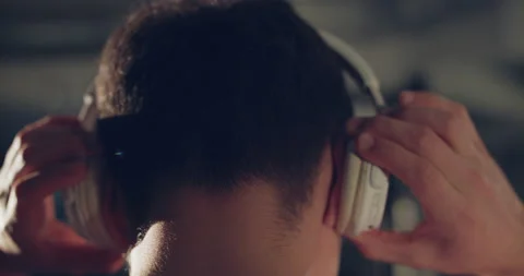 Rear view of male head while hands put headphones on it indoors Video stock 146983273