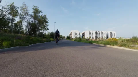 Rear view of a man with a backpack riding a bicycle on an asphalt path head.. Stock Footage 339078776