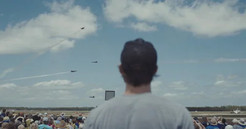 Rear view of man in baseball hat and crowd of people watching airplane show Video stock 147114087