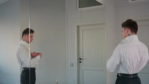 Rear view man buttoning white shirt and adjusting belt by loft studio mirror 스톡 동영상 308664317