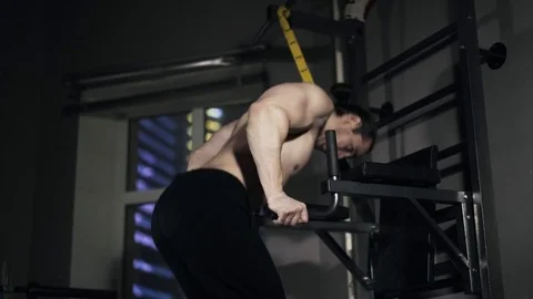 Rear view of a man doing push ups on parallel bars in a gym Stock Footage 74279591