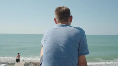 Rear view of man with earphones on beach listening music. Serenity Stock Footage 252148170