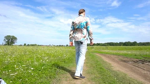 Rear view. A man goes on a through the field Stock Footage 79600153