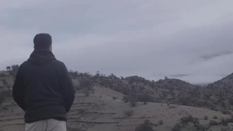 Rear View Man In Hoodie Looking At Foggy Mountains In Morocco Stock Footage 332776531