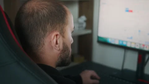 Rear view of a man intently looking at a large computer monitor in a home o.. Stock Footage 327572846