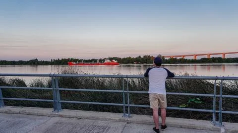 Rear view of a man looking the river, cargo ship Stock Photos