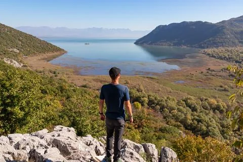 Rear view of man with panoramic view of Lake Skadar National Park in autumn.. Stock Photos