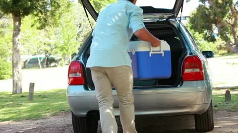Rear view of a man placing his cooler in his car Stock Footage