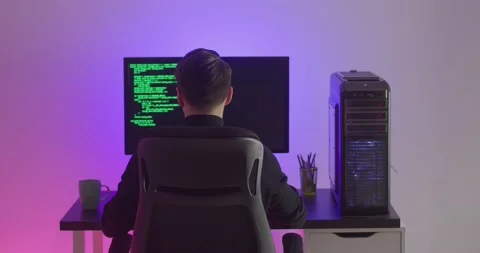 Rear view of man programmer coding network security software indoors in neon Stock Footage 152450834