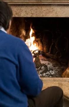 Rear view of a man sitting in front of a fire Stock Photos
