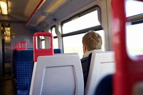 Rear View Of Man Sitting In Train Carriage On Rail Journey Foto stock