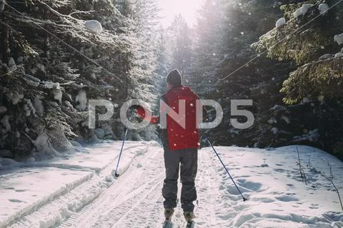 Rear view of man in ski-wear standing on snow covered road Stock Photos