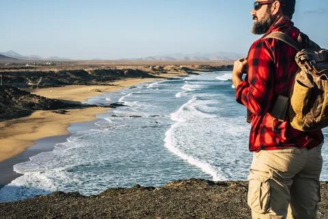 Rear view of man standing with backpack and enjoying the wonderful landscape  Stock-Fotos