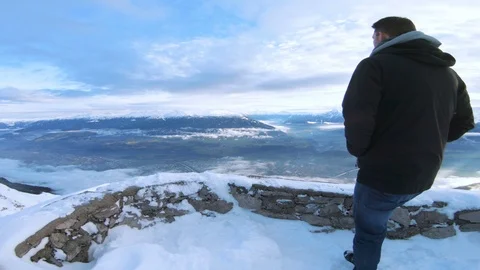 Rear view of man standing on mountain in winter enjoying the landscape Stock Footage 100052914