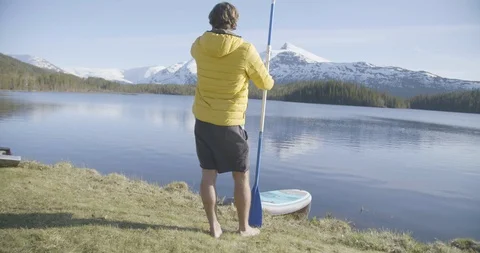 Rear view of man standing with oar near lakeshore Stock Footage 85840192