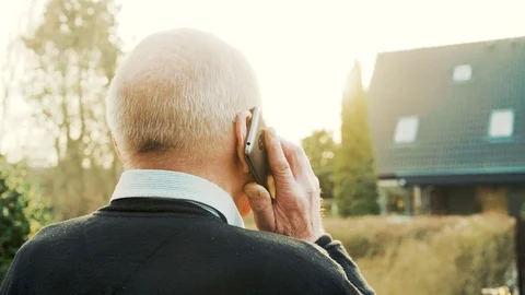 Rear view of man talking on smart phone while he stands outside in sunny weather Stock Footage 104607364
