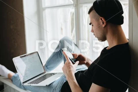 Rear view of man using cellphone and laptop Stock Photos
