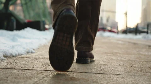 Rear view man walking across city street sidewalk on winter day. Male feet steps Stock Footage 326826787