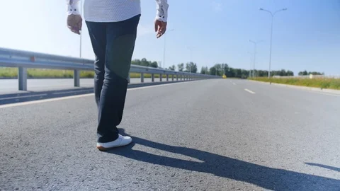 Rear view of a man walking along the road. Close up shot. Stock Footage 114133440