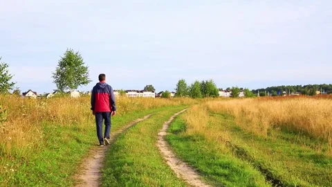 Rear view of a man walking along a rural road on a summer day. Stock Footage 145685713