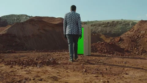Rear view of man walking on red sand in front of the door with green screen Stock Footage 247258812