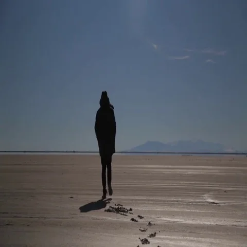 Rear view of man walking in sand on a bright sunny day Stock Footage 69455101