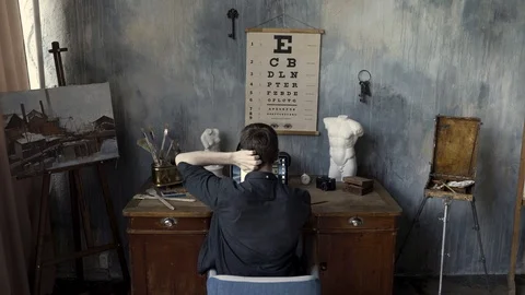 Rear view of a man working on computer in the art studio with a painting Stock Footage 116221039