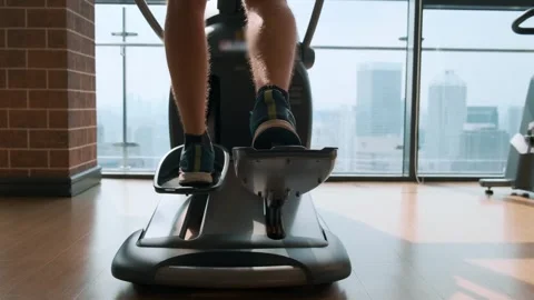 Rear view of man working out on an elliptical trainer in modern gym with city Stock Footage 280942381