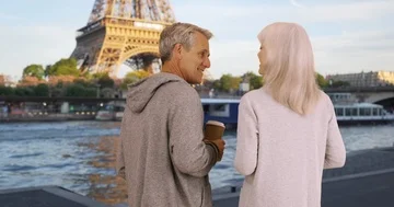 Rear view of mature couple drinking coffee and chatting by the Seine Stock Footage 85608786