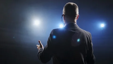 Rear view of men speaking through a microphone in dark conference hall. Man Stock Footage 121592039