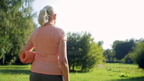Rear view of a middle aged sporty woman going to enjoy exercise in the park Stock Footage 80268438