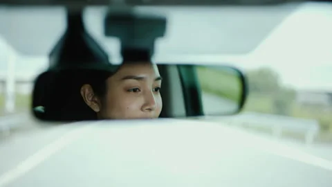 Rear view mirror. Close up shot eye of young asian woman looking roadway. Stock Footage 196052899
