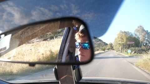 Rear view mirror closeup of young male driver on rural road Stock Footage 112121405