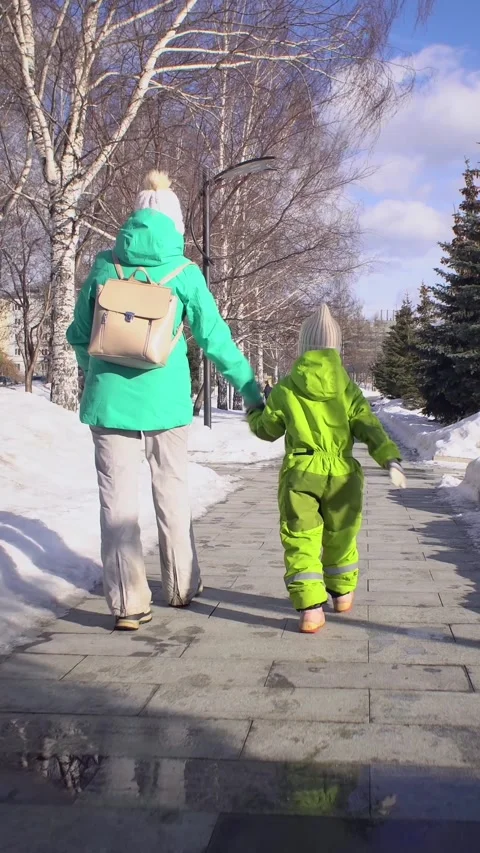 Rear view of mom and kid walk hand in hand on outdoors, vertical shot. Stock Footage 262606848