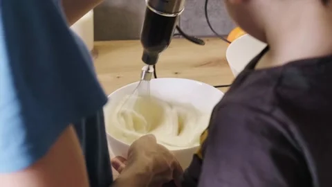 Rear view of a mother with son using the mixer to mix cream from the bowl for Stock Footage 182189509