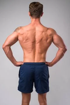 Rear view of muscular man shirtless with hands on hips Studio shot of musc... Stock Photos