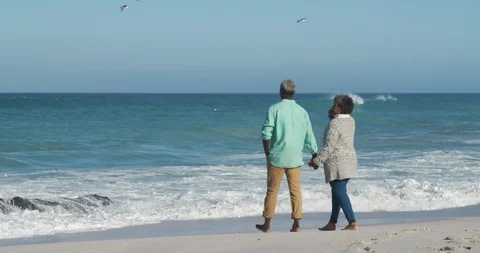 Rear view old couple walking through the beach Stock Footage 125719409