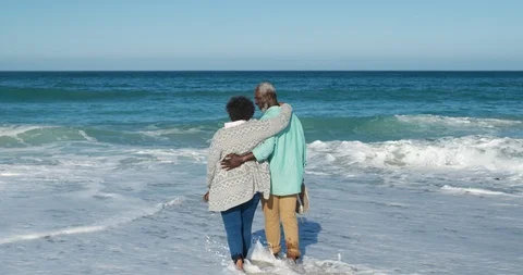 Rear view old couple walking in the water at the beach Stock Footage 125719428