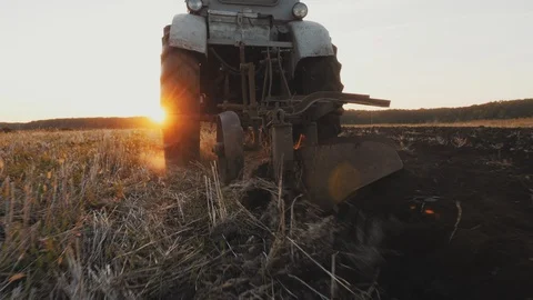 Rear view of an old gray tractor with a harrow at work on a field Stock Footage 104721657