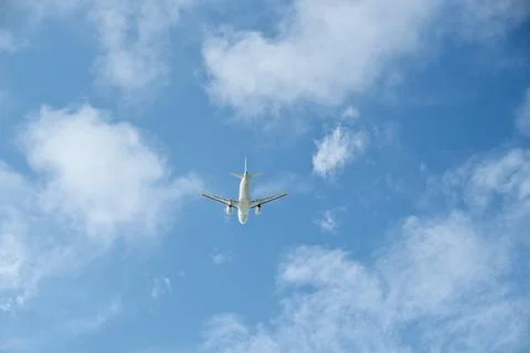 Rear view of a passenger plane flying away into a cloudy sky after takeoff Stock Photos