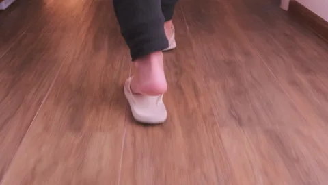 Rear view of person walking in flip flops along indoor apartment hallway with Stock Footage 333651123